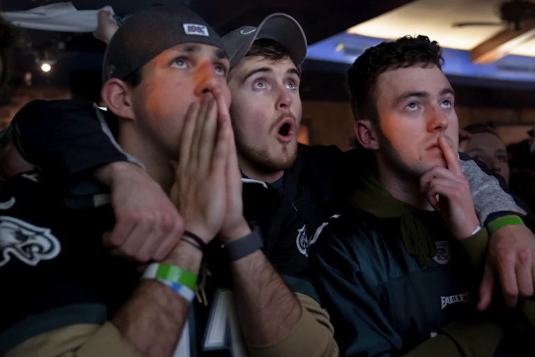 Three male football fans express amazement while watching the Super Bowl.