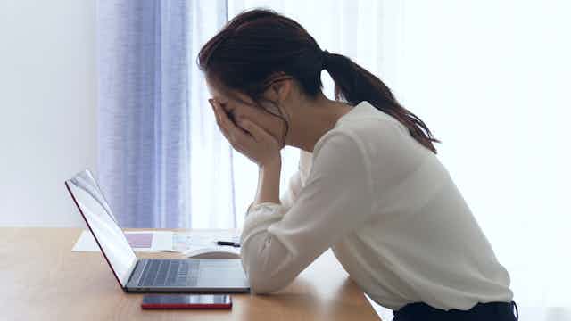 Woman looks distraught will sitting at desk