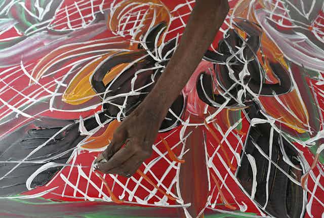 Yolngu artist Dhambit Mununngurr works on a painting during the 2023 Garma Festival. 