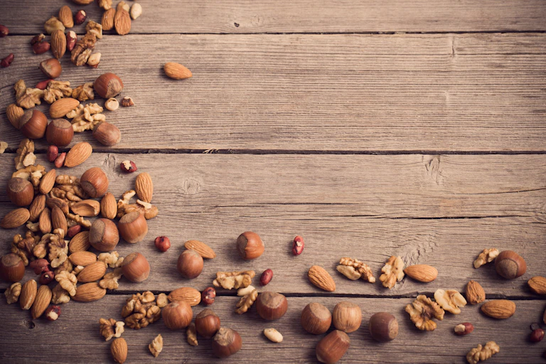 Fotografía de diferentes frutos secos (almendras, avellanas, nueces) sobre una mesa.