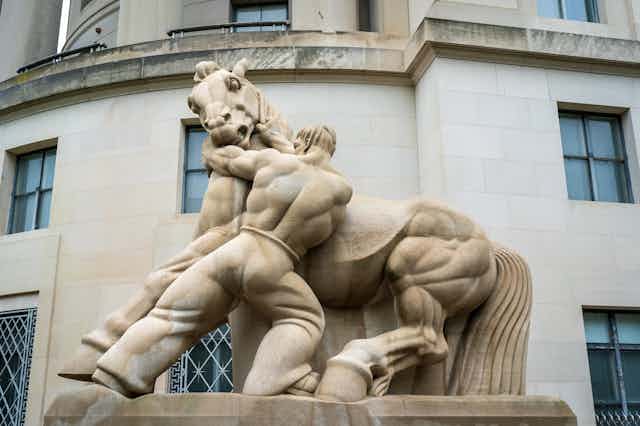 Estatua de un hombre intentando domar a un caballo salvaje.