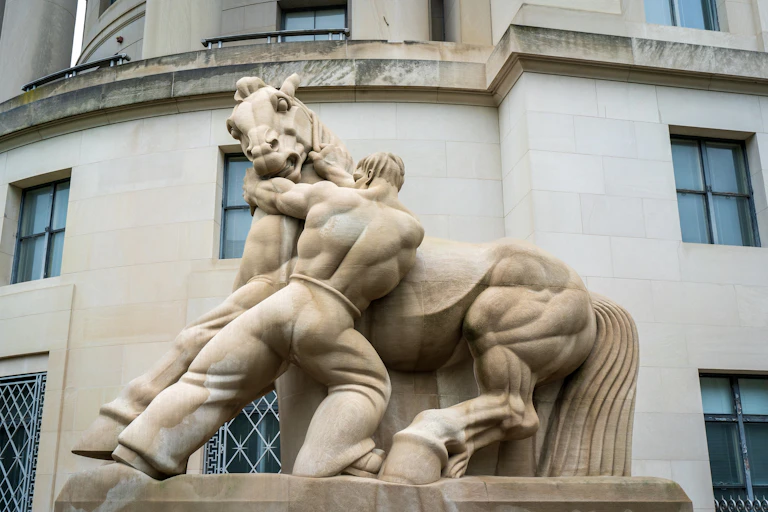 Estatua de un hombre intentando domar a un caballo salvaje.