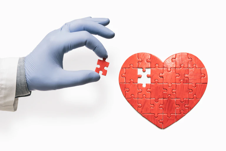 Gloved hand holding the missing puzzle piece to a red heart puzzle
