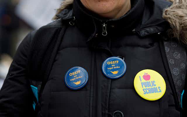 Buttons on a coat say I love public schools and OSSTF on legal strike.