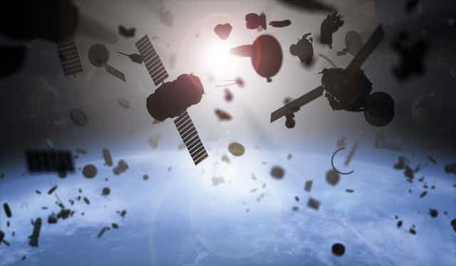 Satellites and assorted pieces of machinery float through space, with Earth seen below and the Sun seen from afar. 