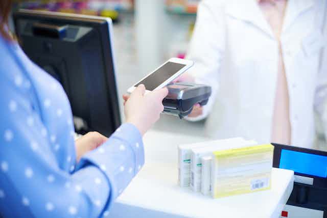 Woman paying for medicines with smartphone at pharmacy