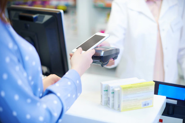 Woman paying for medicines with smartphone at pharmacy