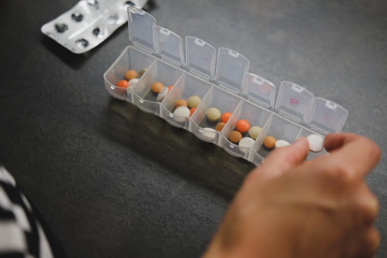 Person adding medications to pill organizer