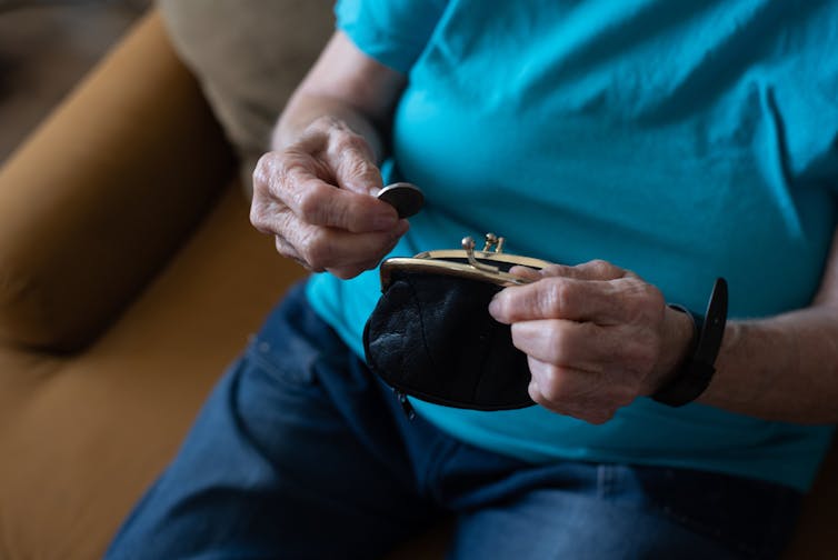 Older woman looking into purse, holding coin