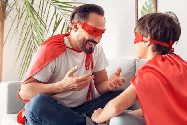 Father and son wearing red capes and masks