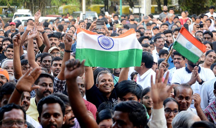 Crowds celebrating India's Moon landing carrying Indian flags.