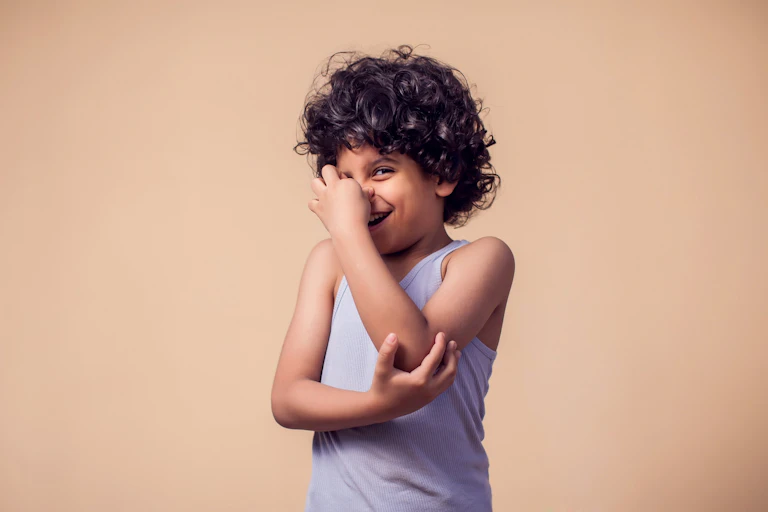 Un niño pequeño se ríe mientras se tapa la nariz.