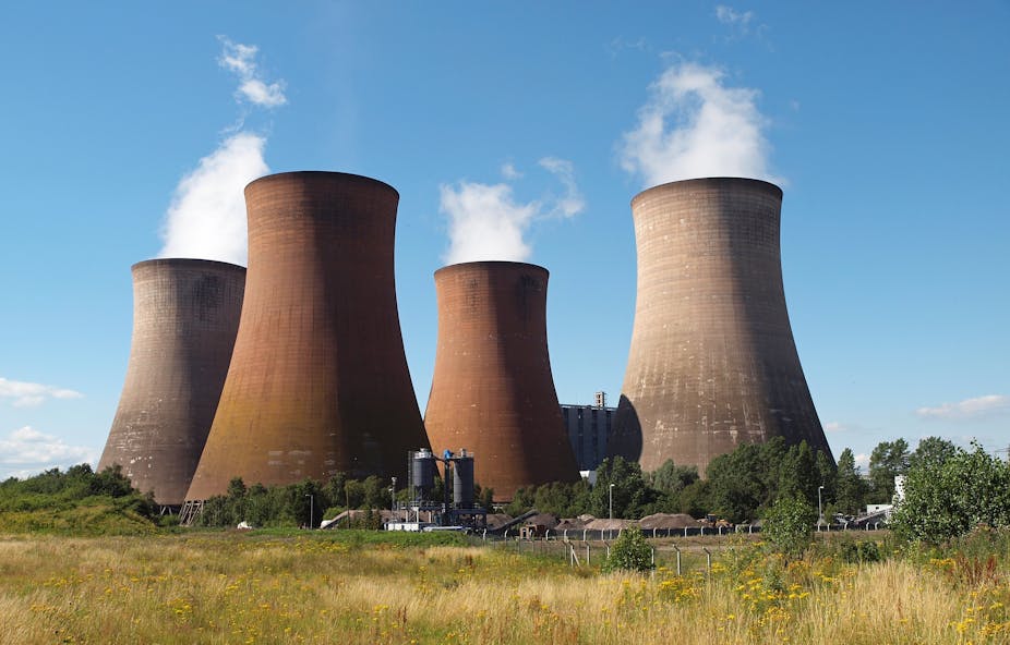 Four enormous industrial chimneys with steam rising from them.