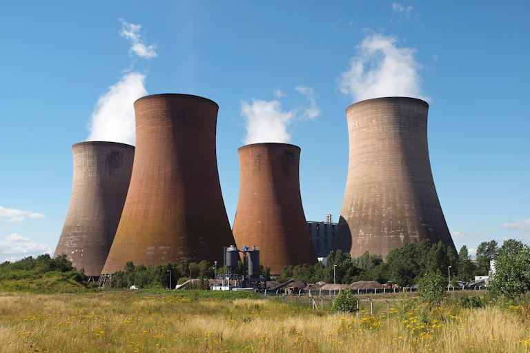 Four enormous industrial chimneys with steam rising from them.