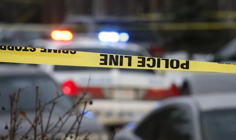 Yellow police tape in front of police cruisers.