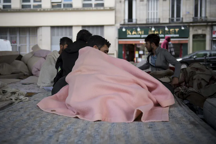 Des hommes assis sur leur matelas dans le camp de migrants du quartier Stalingrad à Paris, le 12 juillet 2023