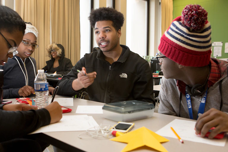 Youth at a table in a classroom in discussion.