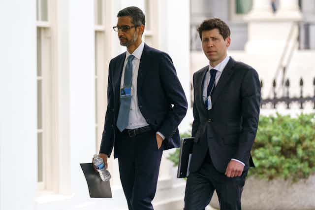 Two men in business suits walk in front of a large building