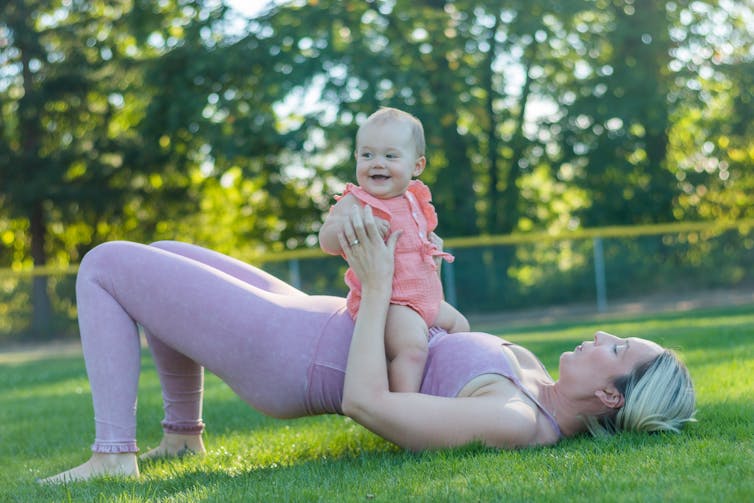 Woman in exercise clothes doing pilates outside with the baby.