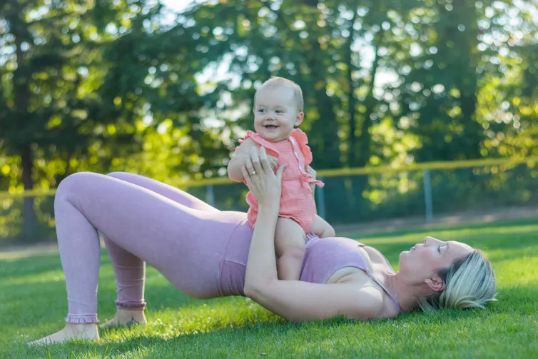 Woman in exercise clothes doing pilates outside with the baby.