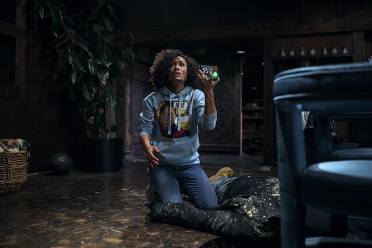 Alison on the floor covered in blood holding a remote.