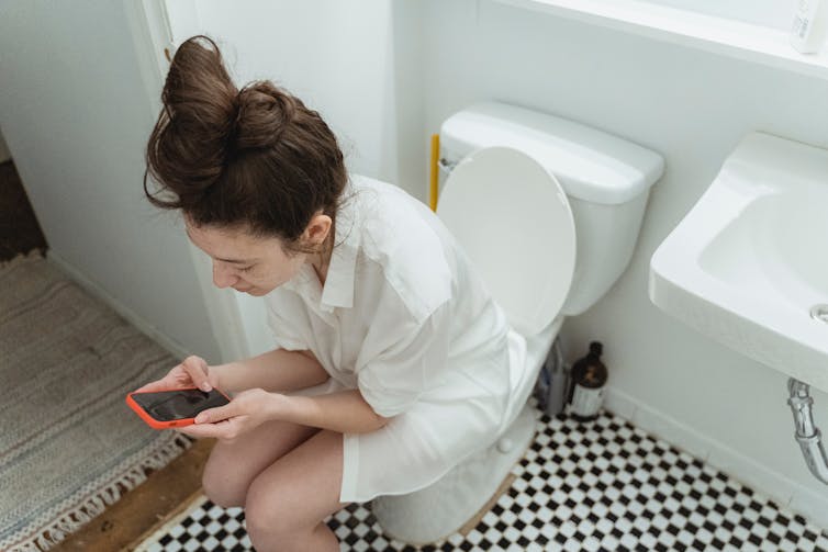 Woman sitting on the loo with ohone.