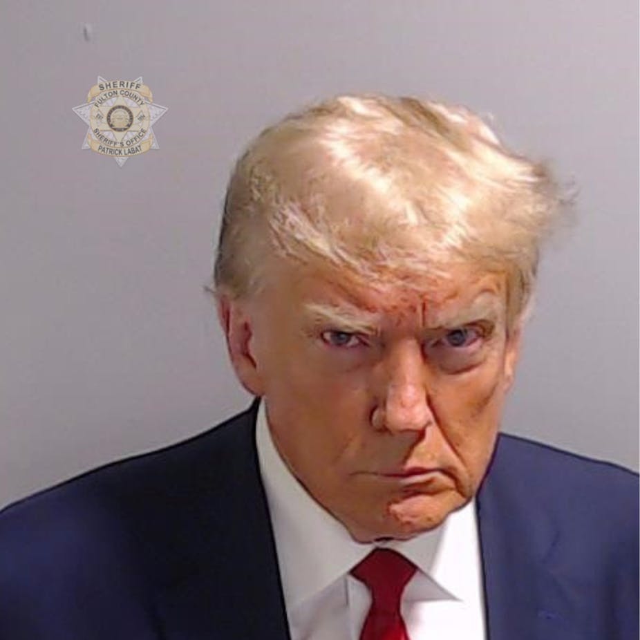 Donald Trump scowls and looks at the camera in a mug shot.