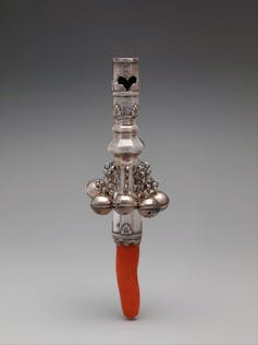 A close-up photo of a tiny red dagger-shaped item with an ornate silver handle.