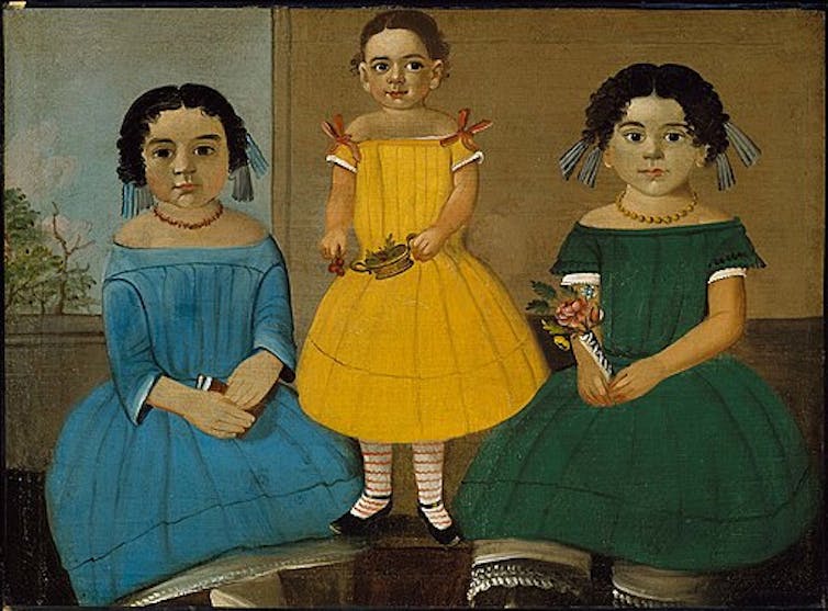 A formal portrait of three young girls in brightly colored dresses.
