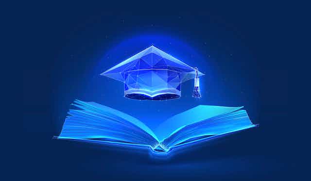 Blue light illuminates a graduation cap that is hovering over an open book.