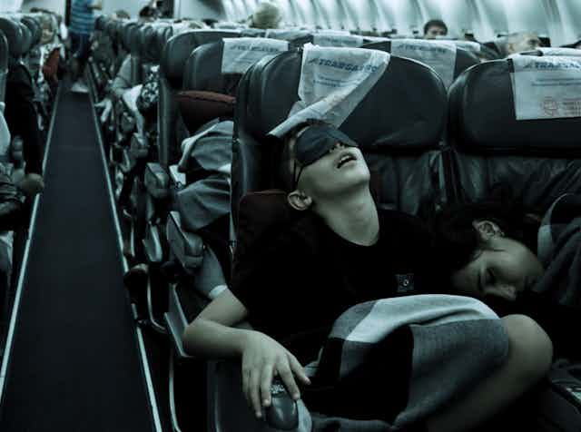 People with sleep masks on a plane with dark surrounds
