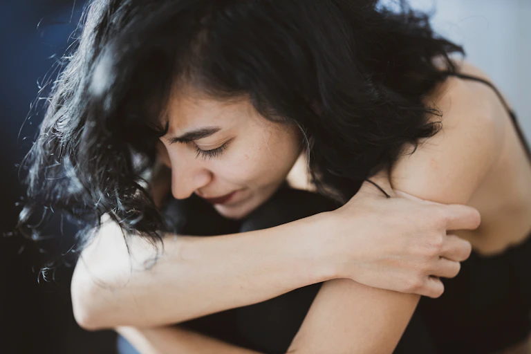 Woman leans over, looking down