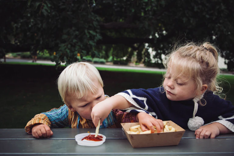 Children eating chips at a park bench