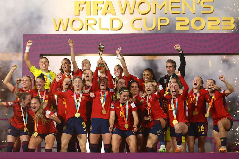 Imagen de las jugadoras y el entrenador de la selección española de fútbol alzando la Copa del Mundo.