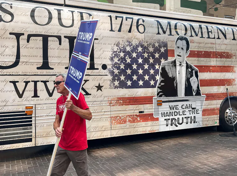 A Donald Trump supporter walks past a bus promoting Republican presidential contender Vivek Ramaswamy.