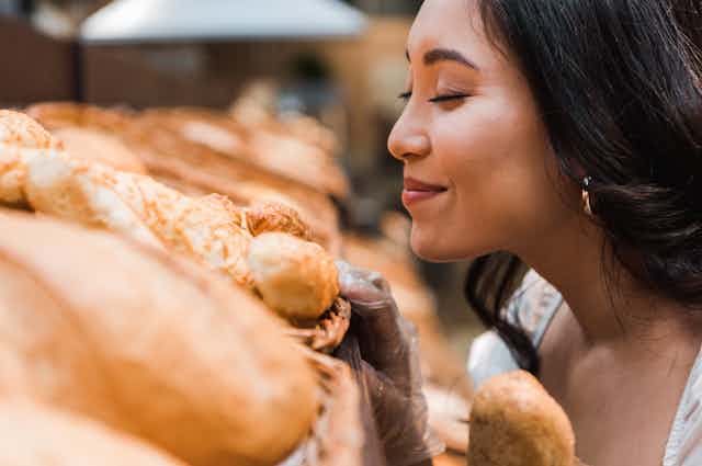 Woman smelling loaves of bread.