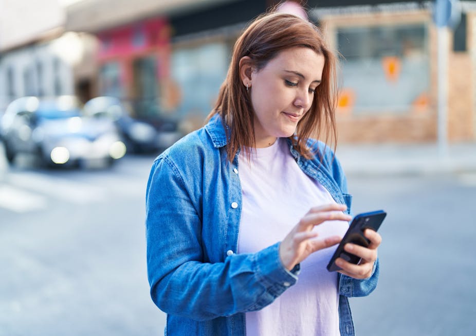 A young woman looks at her smartphone.