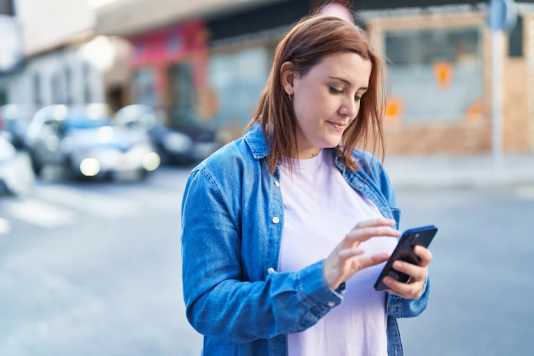 A young woman looks at her smartphone.