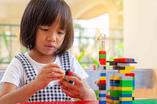 A young girl playing with Lego blocks.
