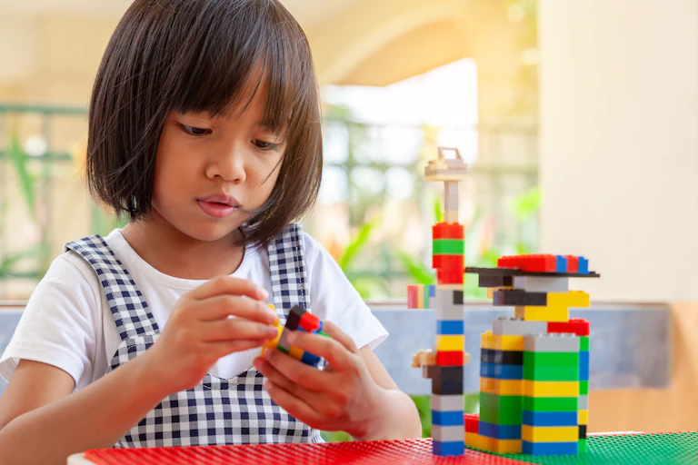 A young girl playing with Lego blocks.