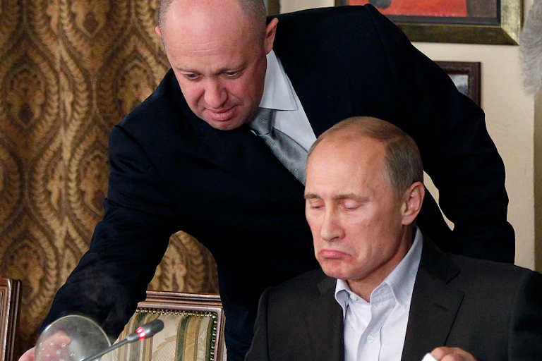 Yevgeny Prigozhin leans over to pour wine for Vladmir Putin