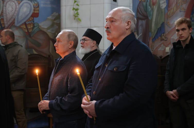 Vladimir Putin and Alexander Lukashenko hold candles in a church in Karelia, Russia, July 2023.
