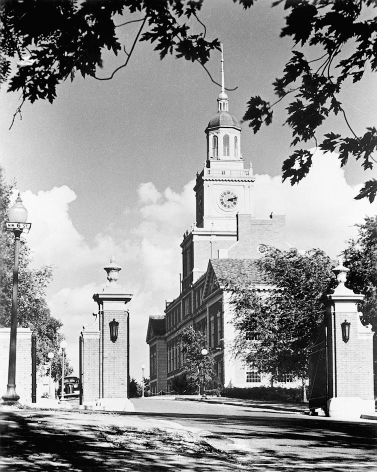 A black-and-white image shows a large building with a clock tower.