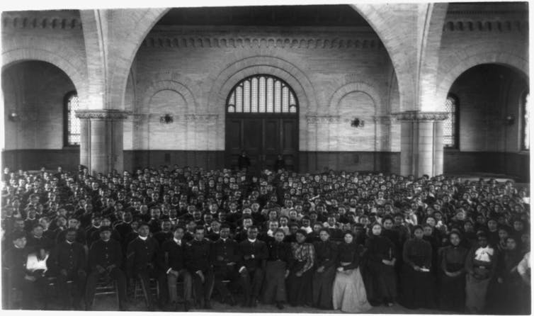 Scores of Black students are standing in rows for a school assembly.