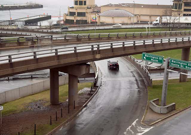 A photo of an interchange with buildings and a seafront in the background.
