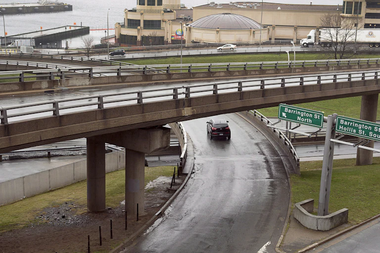 A photo of an interchange with buildings and a seafront in the background.
