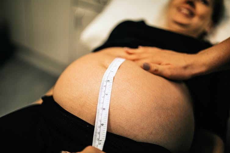 Midwife or doctor measuring pregnant woman with tape measure