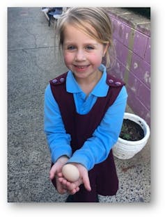 A student holds an egg at the after-school chicken coop project.