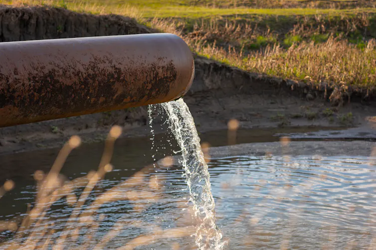 A pipe releasing wastewater into a river.