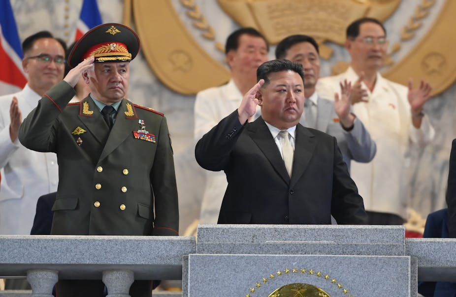 Russian defence minister Sergei Shoigu stands on balcony next to North Korean lader Kim Jng-un as they both salute a military parade
